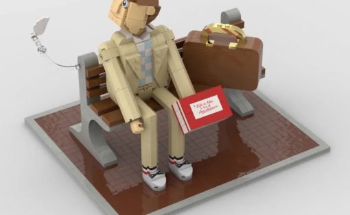 LEGO figure sitting on a bench with a brown suitcase and a red card on a tiled floor.