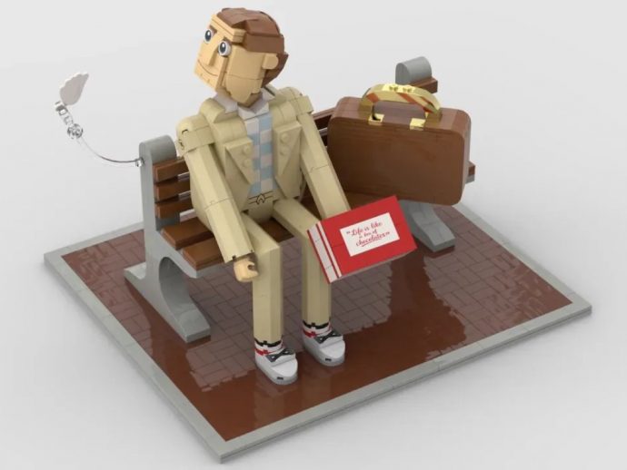 LEGO figure sitting on a bench with a brown suitcase and a red card on a tiled floor.
