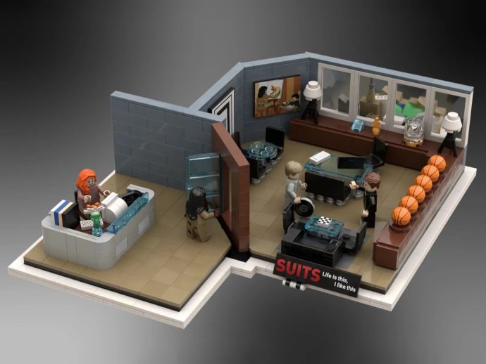 LEGO office diorama showing a modern open workspace with a glass desk, basketballs along a bench, and two coworkers conversing near a conference area labeled SUITS Life is this, I like this