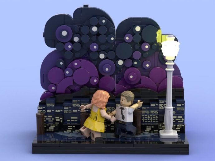 LEGO scene of a man in a white shirt and tie dancing with a woman in a yellow dress on a brick platform beside a tall street lamp, against a purple circular backdrop.