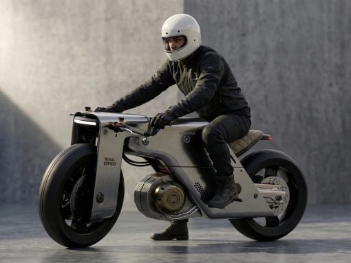 Rider in a white helmet and black gear leans forward on a silver Royal Enfield motorcycle.
