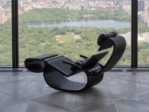 Industrial-style lounge chairs with curved black slats arranged near a large window overlooking a city park and river.