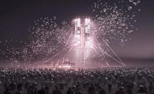 Large nighttime crowd surrounding a glowing rocket-like stage with pink lights and rising bubbles, creating a festive atmosphere
