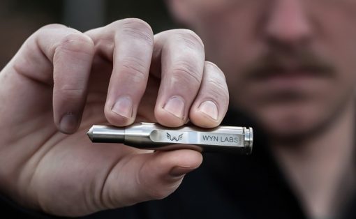 Close-up of a hand holding a small silver device labeled 'WYN LABS'.