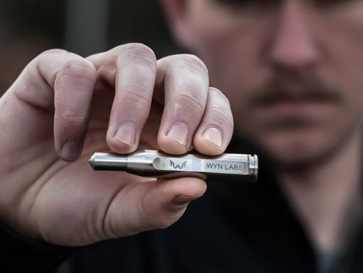 Close-up of a hand holding a small silver device labeled 'WYN LABS'.