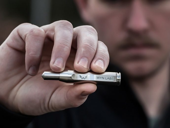Close-up of a hand holding a small silver device labeled 'WYN LABS'.