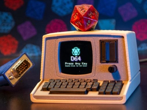 Retro toy computer with a red 20‑sided die perched on top; screen shows '064' and 'Press Any Key' with a small keyboard in front.