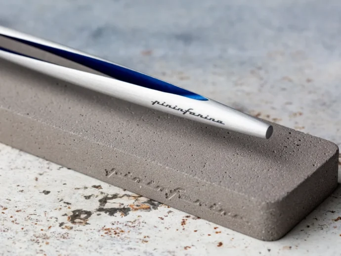 Metal knife-sharpening rod with blue accent resting on a gray whetstone edge.