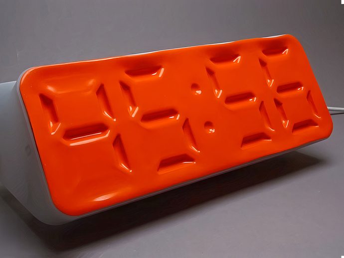 Orange rectangular baking mold with twelve shallow rectangular depressions on a light stand, set on a gray surface.