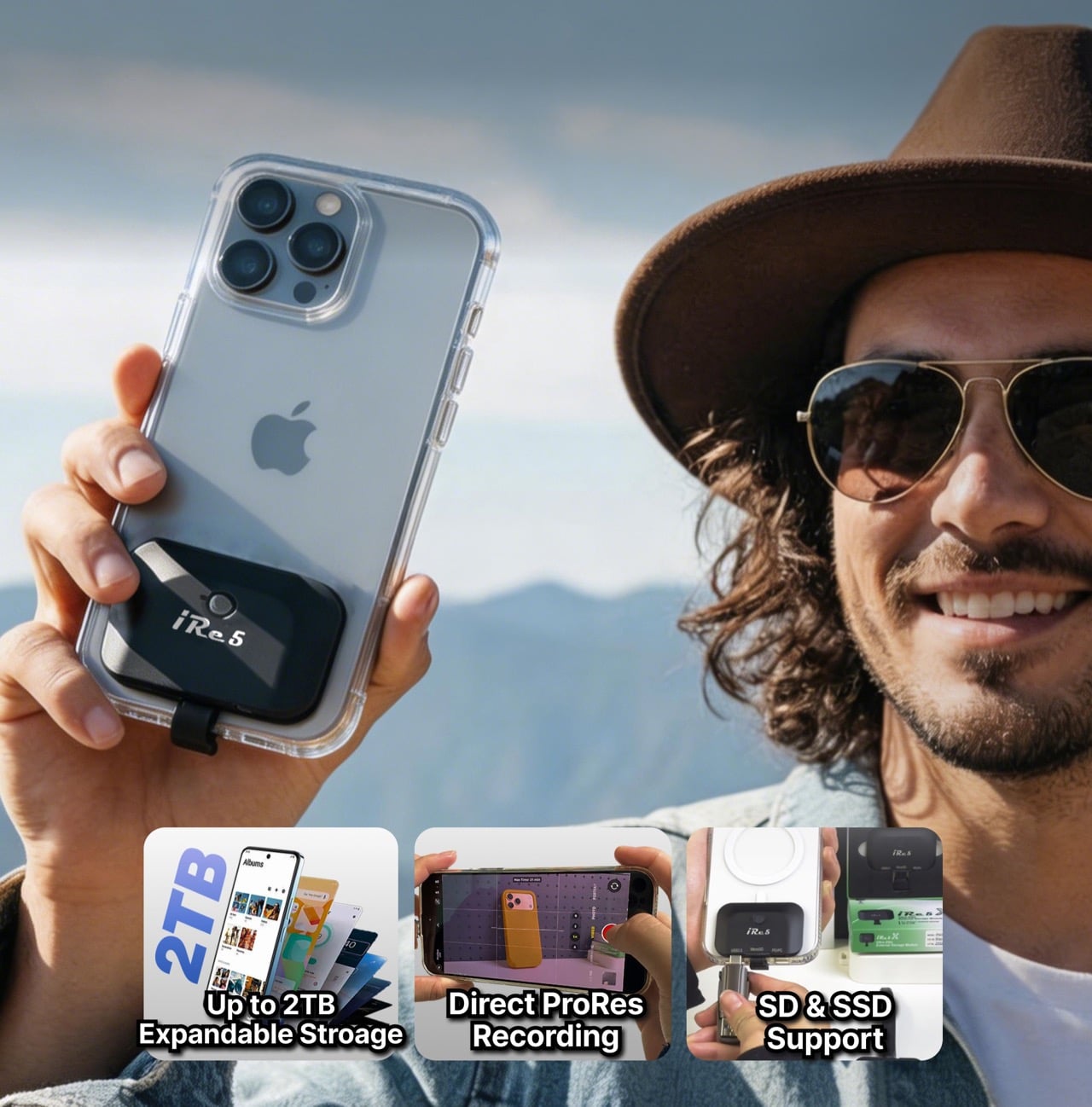 Man wearing a brown hat and aviator sunglasses holds up a smartphone with a clear case and a clip-on accessory on the back, outdoors.