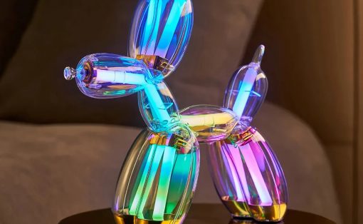 Colorful illuminated balloon animal sculpture shaped like a dog, with rainbow lights on a round pedestal.