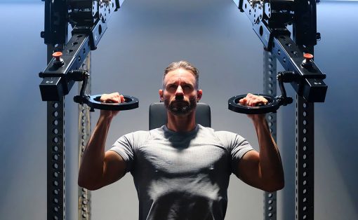 Man in a gray t-shirt performing a chest press on a cable machine in a gym.