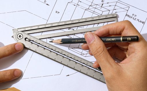 Architect's hand using a metal ruler and pencil over blueprints for drafting work on a desk