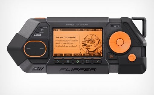 Handheld black portable Linux computer with orange UI, large right circular control, left thumb pad, and 'FLIPPER' label.