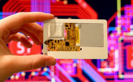 Hand holding a small gold circuit board with exposed components against a neon, abstract background.