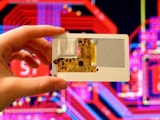 Hand holding a small gold circuit board with exposed components against a neon, abstract background.