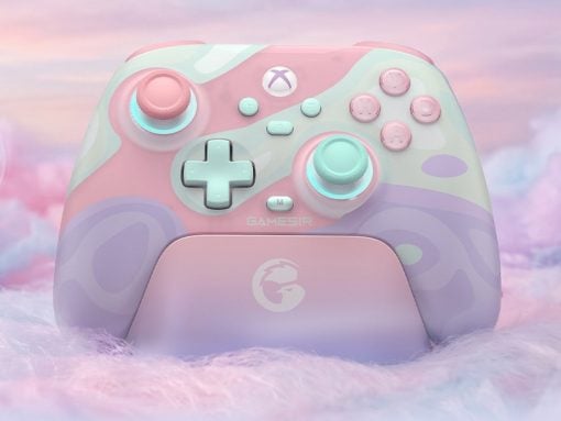 Pastel pink and mint Xbox wireless controller on a matching charging dock with a fluffy pastel backdrop.