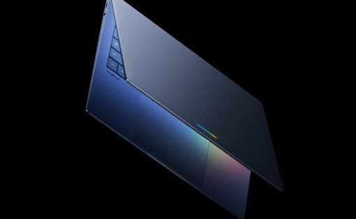 Slim blue laptop opened at an angle against a black background, showing a backlit keyboard and a colorful glow on the touchpad area.