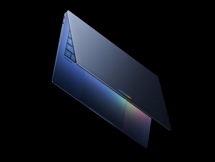 Slim blue laptop opened at an angle against a black background, showing a backlit keyboard and a colorful glow on the touchpad area.