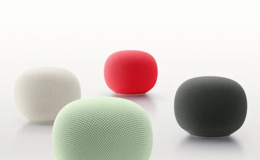 Four round, fabric-covered smart speakers in white, red, mint green, and gray on a white surface.