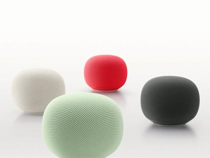 Four round, fabric-covered smart speakers in white, red, mint green, and gray on a white surface.