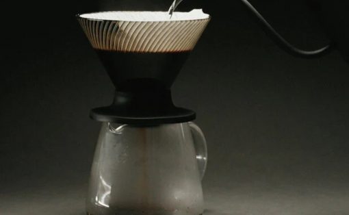 Pour-over coffee setup: a coffee filter sits atop a glass carafe against a dark background, ready for brewing on a countertop.