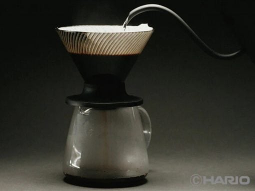 Pour-over coffee setup: a coffee filter sits atop a glass carafe against a dark background, ready for brewing on a countertop.