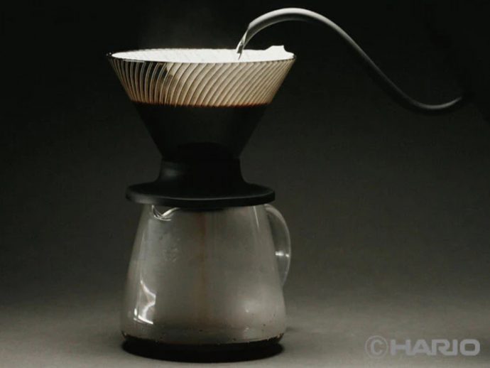 Pour-over coffee setup: a coffee filter sits atop a glass carafe against a dark background, ready for brewing on a countertop.