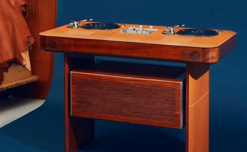 Retro wooden DJ console with two turntables on top and a speaker cabinet underneath, against a blue backdrop.