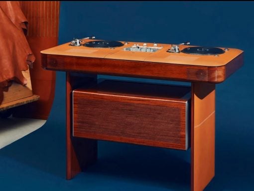 Retro wooden DJ console with two turntables on top and a speaker cabinet underneath, against a blue backdrop.