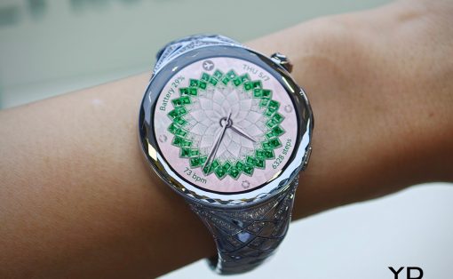 Close-up of a silver wristwatch on a bare wrist with a green geometric rosette dial and braided band.