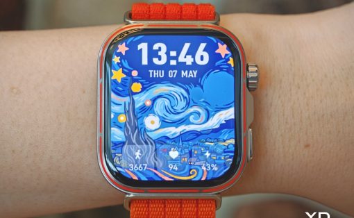 Smartwatch with orange band on the wrist, showing a Starry Night–inspired face and the time 13:46.