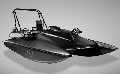 Black-and-white photo of a futuristic speedboat with a streamlined hull and open cockpit, appearing to float in midair in a studio setting.
