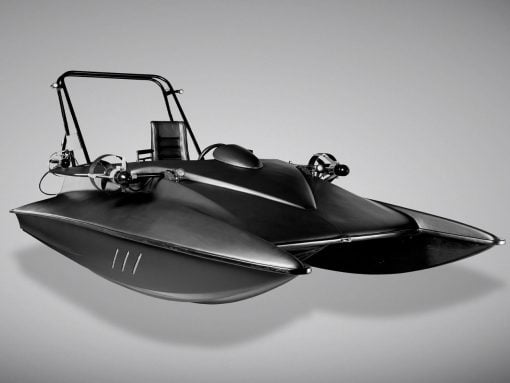 Black-and-white photo of a futuristic speedboat with a streamlined hull and open cockpit, appearing to float in midair in a studio setting.