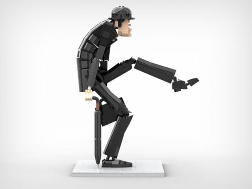 LEGO minifigure in dark armor and helmet stands on a white display base, bending forward and reaching outward with a long black tool-like piece in one hand.
