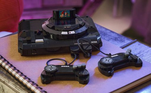 Retro Sega Mega Drive console with two wired controllers on a purple-toned notebook.