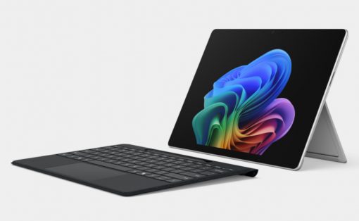 Tablet with detachable keyboard and stand, screen showing colorful abstract wallpaper on a light background.
