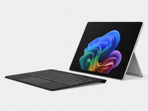 Tablet with detachable keyboard and stand, screen showing colorful abstract wallpaper on a light background.