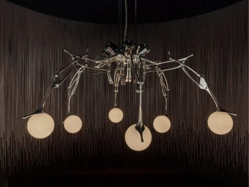 Contemporary metal chandelier with multiple curved arms and glowing glass bulbs in a dark room.