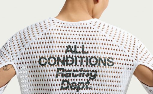 Back view of a person wearing a white perforated mesh shirt with the text 'ALL CONDITIONS Racing Dept.' printed on the back.
