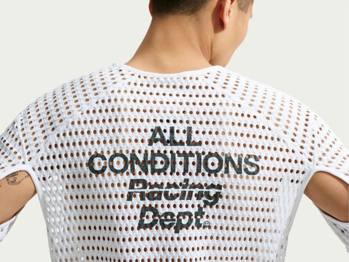 Back view of a person wearing a white perforated mesh shirt with the text 'ALL CONDITIONS Racing Dept.' printed on the back.