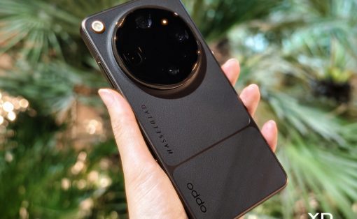 Back of a black Oppo smartphone with a large circular camera module labeled Hasselblad, held in a hand outdoors.