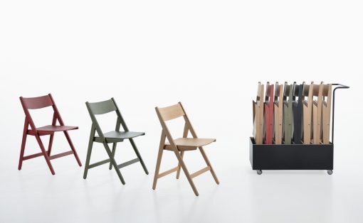 Three folding chairs in red, gray-green, and natural wood tones arranged left to center, with a wheeled black rack of color samples on the right