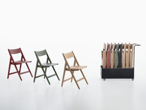 Three folding chairs in red, gray-green, and natural wood tones arranged left to center, with a wheeled black rack of color samples on the right