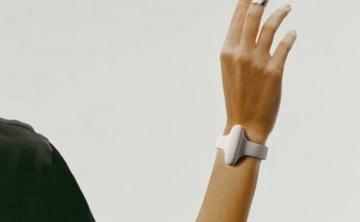 Person's arm is raised, wearing a white minimalist wrist-worn device with a clasp around the wrist.