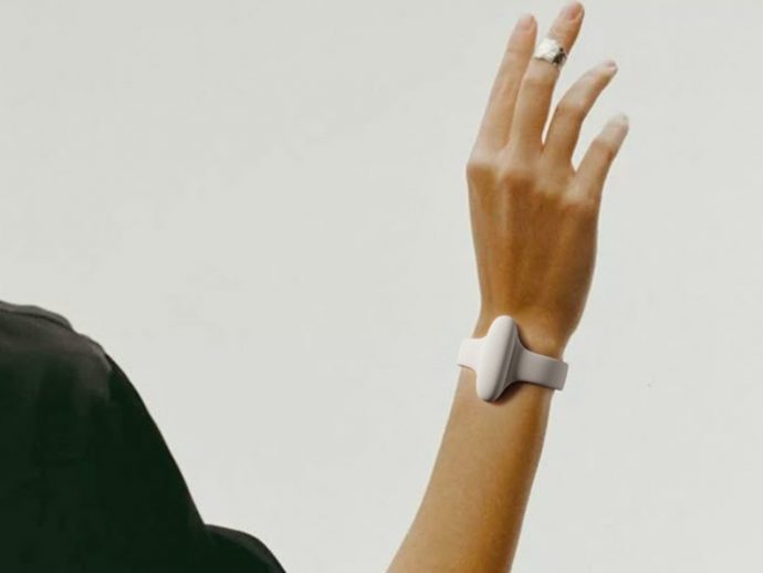 Person's arm is raised, wearing a white minimalist wrist-worn device with a clasp around the wrist.
