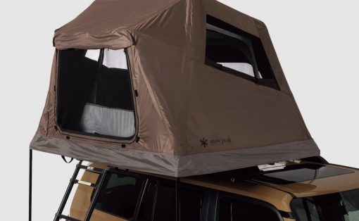 Brown rooftop tent mounted on a gold SUV with a folding ladder extending to the ground, side entry open.
