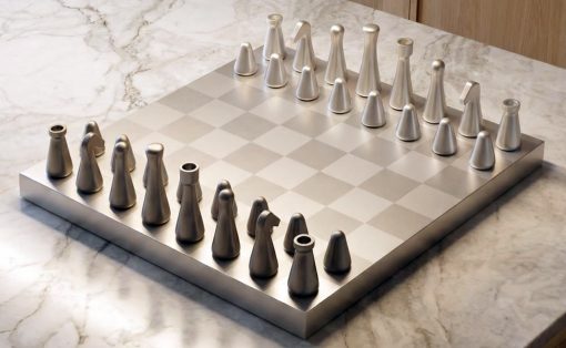 Metal chess set with abstract conical pieces arranged on a square board atop a marble countertop.