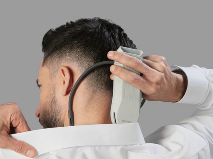 Man getting a neck trim with a cordless hair trimmer held behind his ear in a barber’s chair.