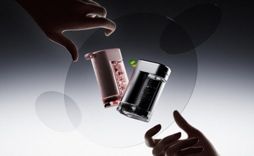 Two hands reach toward mid-air glass vials and a black-and-pink bottle, suspended inside translucent rings against a gray gradient background.